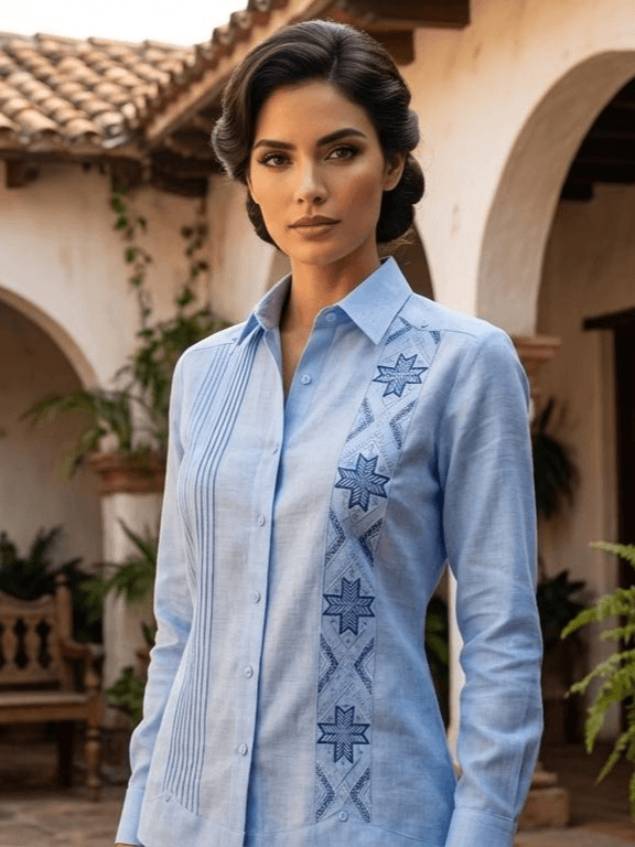 Camisa guayabera de manga larga en color azul claro con una franja de bordados de estrellas en azul oscuro y pliegues verticales, exhibida en un maniquí.