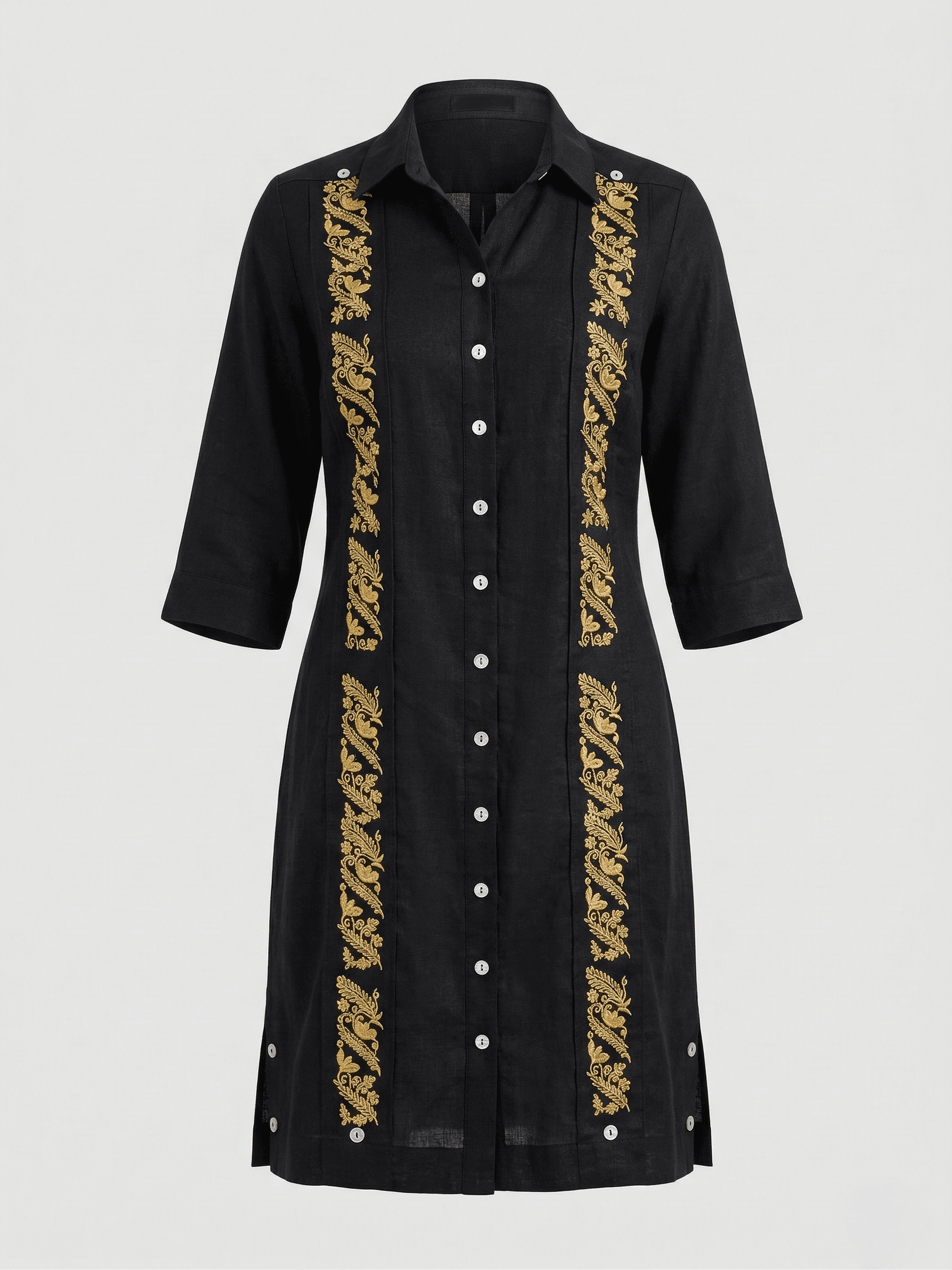 Vestido tipo camisero de color negro intenso con dos franjas verticales de bordados florales en hilo dorado brillante. El diseño presenta botones frontales blancos, cuello estructurado y mangas 3/4. Se aprecian detalles de botones en las aberturas laterales inferiores sobre un fondo gris neutro