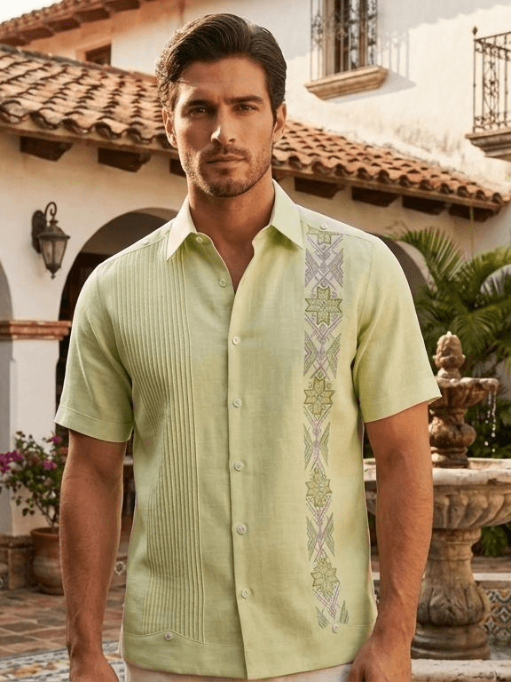 Camisa guayabera de manga corta en color verde lima claro con una franja de bordados de estrellas verdes y lilas en un costado y pliegues tradicionales en el otro.