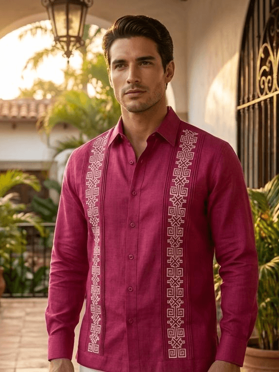 Camisa guayabera de manga larga en color rojo intenso con dos columnas de bordados geométricos de color crema, presentada en un maniquí sobre un fondo rústico.