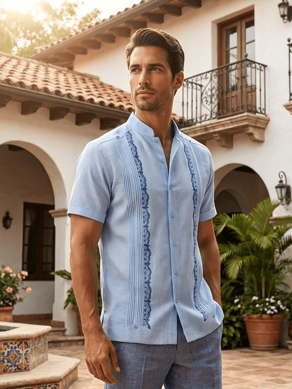 Camisa guayabera de manga corta en azul muy pálido con bordados decorativos en azul oscuro y cuello mandarín, inspirada en el clima de Jinotega.
